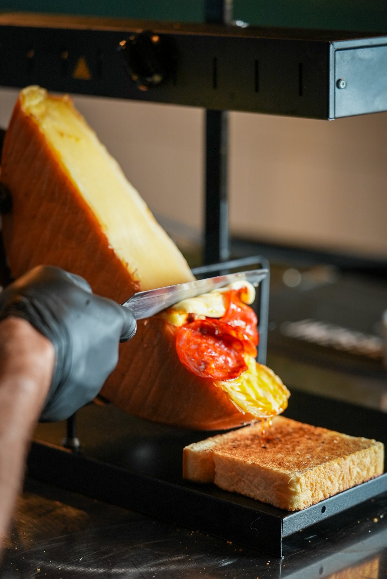Roztopiony ser raclette z chorizo podawany na pieczywie